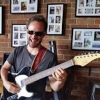 a man in sunglasses playing an electric guitar